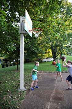 three young boys playing basketball in the park