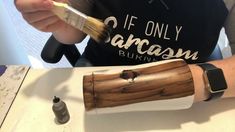 a person is holding a brush over a piece of wood that has been carved to look like an arm