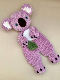 a pink teddy bear with a green leaf on it's back laying next to another stuffed animal