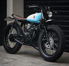 a blue and white motorcycle parked in front of a garage