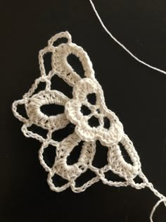 a crocheted piece of white yarn sitting on top of a black table next to a string