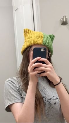 a woman taking a selfie in front of a mirror wearing a knitted hat