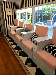 some pink and white couches sitting in front of a window with black and white striped walls