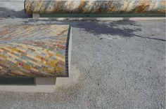 two benches sitting next to each other on top of cement ground with colorful tile covering them