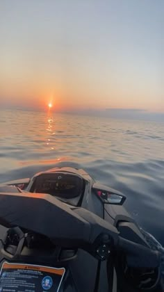 the sun is setting over the ocean as seen from a motorboat in the water