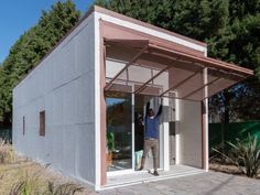 a man standing in the doorway of a small building with his hands up to the ceiling