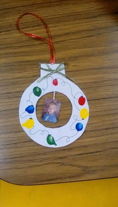 a christmas ornament hanging from a wooden table with a photo on the front