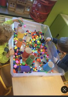 two children are playing with toys in a play area at the table and on the floor