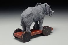 an elephant figurine sitting on top of a wooden cart