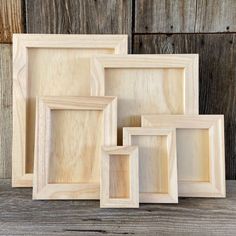 four wooden frames sitting next to each other on top of a wooden table with wood planks in the background