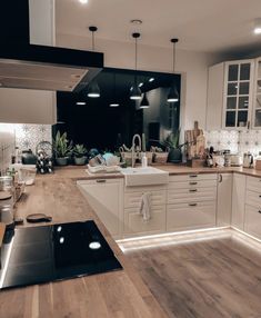 a kitchen with wooden floors and white cabinets, lights on the counter top and floor