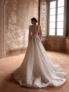 a woman in a white wedding dress standing on a tile floor with her back to the camera