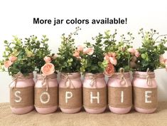 pink mason jars filled with flowers and the word'sophiie'painted on them