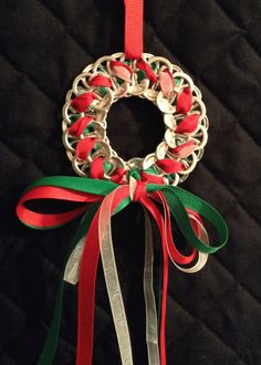 a christmas wreath ornament hanging from a red ribbon on a black quilted background