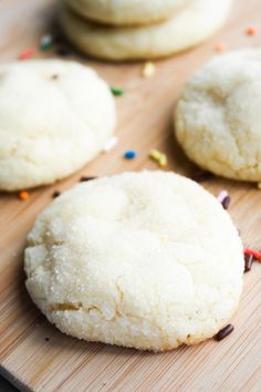 three sugar cookies on a cutting board with sprinkles