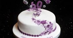 a white birthday cake with purple flowers on top