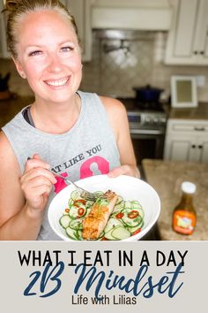 a woman holding a plate of food with the words what i eat in a day