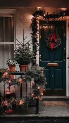 christmas wreaths on the front door of a house decorated with lights and evergreen garland