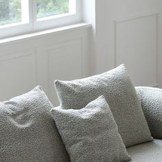 three pillows sitting on top of a couch next to a window