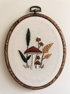 a close up of a embroidery on a white surface with mushrooms and leaves in it