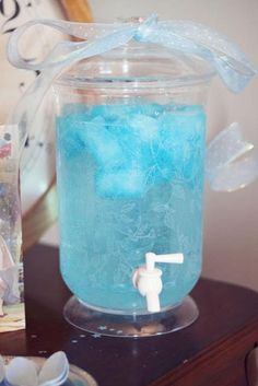 a glass jar filled with blue liquid on top of a table