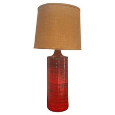 a red glass table lamp with a brown shade on it's base and a beige linen lampshade