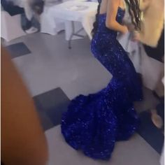 a woman in a long blue dress dancing on the dance floor with other people around her