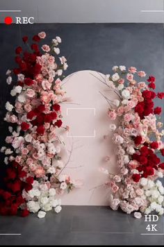 an arrangement of flowers is displayed in front of a gray background with red, white and pink colors