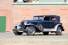 an old blue car parked in front of a brick building