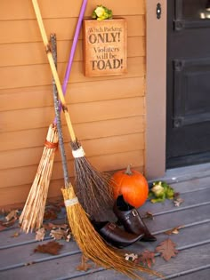 two brooms sitting on top of a pile of leaves next to a house door