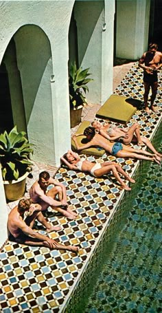 several men and women lounging in the sun by a swimming pool with tiled floors