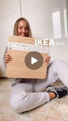 a woman sitting on the floor holding up a cardboard box that says ikea hack