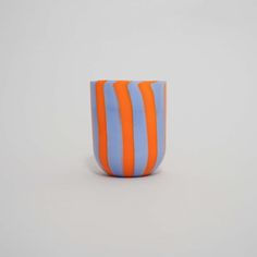 an orange and blue striped vase sitting on top of a table