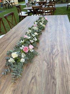 a table with flowers and greenery laid out on it in the shape of a line