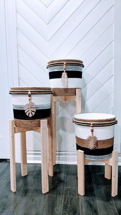 two white and black baskets sitting on top of wooden stools next to each other