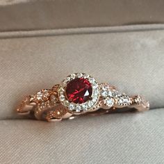 a red and white diamond ring sitting on top of a cushion