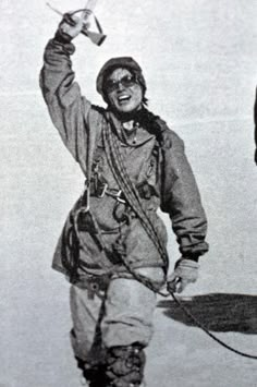 an old black and white photo of a man in uniform holding up a toy airplane