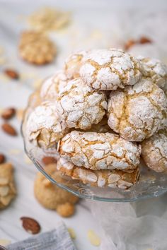 a glass bowl filled with cookies and powdered sugar on top of a white table cloth