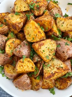 a white plate topped with potatoes covered in parsley