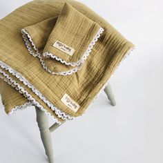 three pieces of cloth folded on top of a wooden stool with lace trimming around the edges