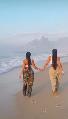 two women walking on the beach holding hands