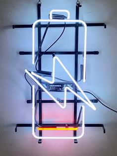 a neon sign that is hanging from the side of a wall with wires attached to it