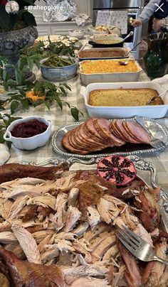 an assortment of meats and other foods on a table with people in the background