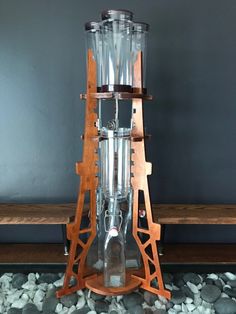 a wooden stand with two large glass bottles on it's legs and one is holding a wine bottle