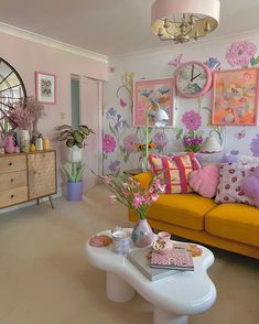 a living room filled with lots of furniture and flowers on the wall behind the couch