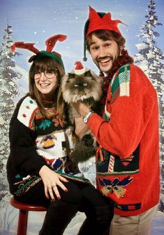 a man and woman in ugly ugly sweaters holding a dog