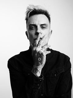 a man with tattoos on his face and hands covering his mouth