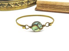 Crafted from brass and featuring genuine abalone, this modernist piece is perfect for those who love bohemian accessories. It has interior dimensional of 2 1/8" x 1 7/8" making it suitable for a smaller sized wrist. Boho Bangle Bracelets, Boho Bangle, Bohemian Accessories, Bangle Bracelet, Bangle Bracelets, Bangles, Brass, Bracelet, Trending Outfits