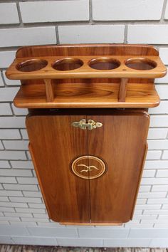 an old fashioned wooden cabinet with four cups on it's top and two doors open