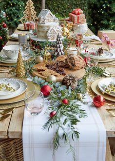 the table is set for christmas dinner with plates, silverware and other holiday decorations